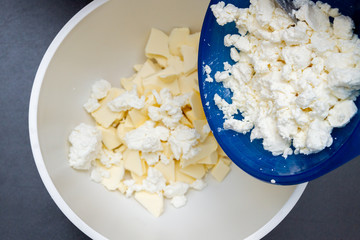 Adding cottage cheese to pieces of butter in a bowl for making cookies