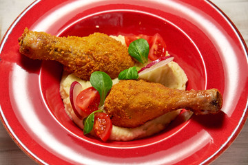 Chicken legs on the side with mashed potatoes. Light wooden background. Restaurant menu