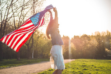 Happy women patriot running in the field with American flag. USA celebrate 4th of July