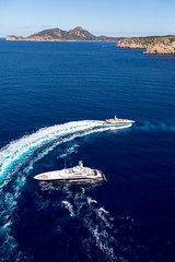 Aerial view of luxury big yachts on sea. Big motor yacht running around the luxury yacht creating...