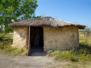 Fototapeta na wymiar Mud hut with a reed roof, archaeological park 