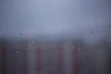 Close-up of raindrops on the window on a blurred background of the city in the evening