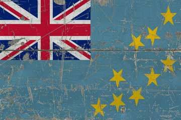 Grunge Tuvalu flag on old scratched wooden surface. National vintage background.