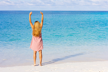  Beautiful young girl on the beach. Young blonde is standing back to the camera