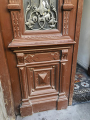 Glass wooden door of a building on the street with an iron decorative ornament. Old Tbilisi architecture