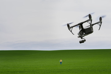 Man goes to the field. Man from behind, a quadrocopter is flying behind him.