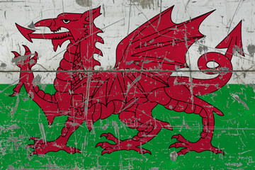 Grunge Wales flag on old scratched wooden surface. National vintage background.