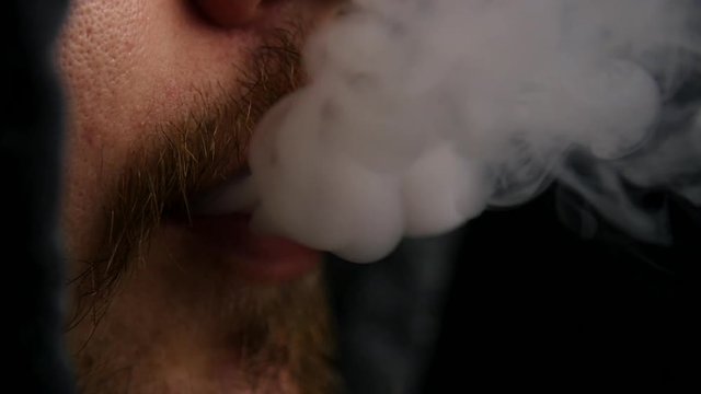 Male exhales vapor in slow motion.