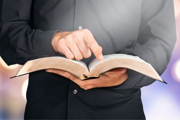 Closeup on a Priest Holding a Bible and Pointing Finger