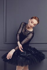 Ballerina in a black tutu posing on a black background.
