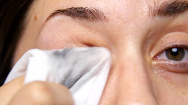 Woman removes eye makeup.