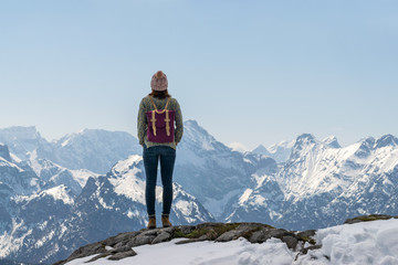 Girl with purple backpack standing on mountain peak looking to beautiful view over the european...