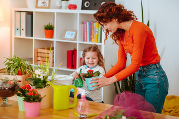 Mom taking care of plants with her funny excited daughter