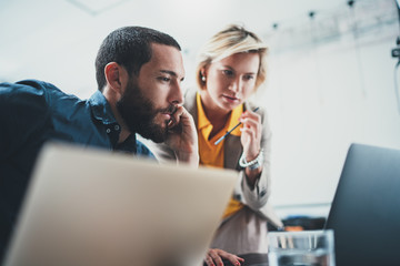 Closeup view of two young coworkers working on mobile laptop computer at office