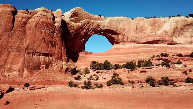 Aerial, drone shot, of a man walking on Utah arch skyline, on a sunny day, in Arches national park, USA