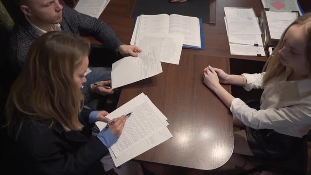 Caucasian Couple Checking Contracts For New Real Estate Property Before Signing in Front of Female Realtor in Office. Light Camera Movement