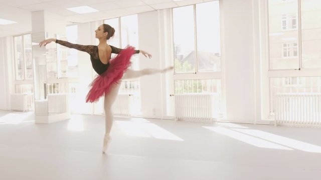 Professional ballerina dancing in a bright studio, medium to wide tracking shot