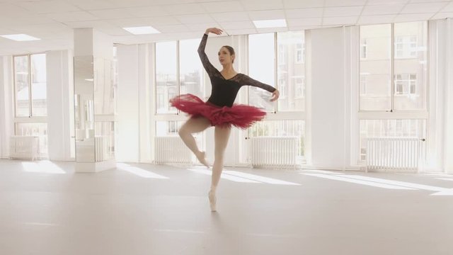 European ballet dancer practicing her techniques in a bright studio, wide to medium tracking shot