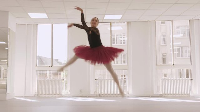Professional ballerina jumping in screen, wide slow motion shot