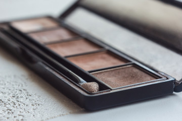 box set of eye shadows and face powder close up on a white table. decorative cosmetics pallets close-up on blurred background