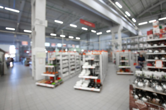 Blurred concept of DIY shopping center. Shelving with household products and kitchenware. Commercial LED lighting. Merchandising in retail.