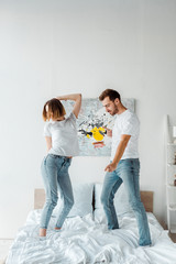 Full length view of couple in jeans dancing on bed