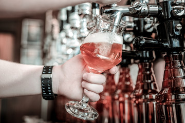 Bartender's hands filling a glass with draught beer.