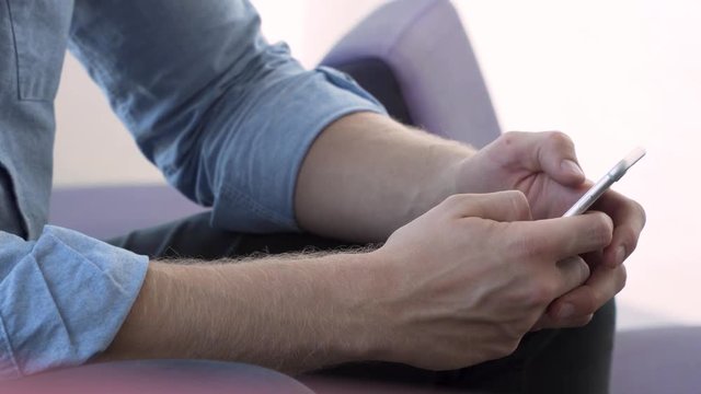 Close up caucasian smartphone male hands texting on cellphone at work. A young male using a smart phone in the office sending a direct message on Instagram.