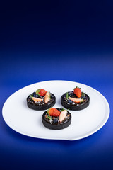 Cookie crust chocolate tart with Blueberry and strawberry set on Blue Background.