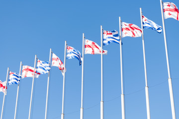 Flags of Georgia and Batumi city waving against blue sky on a clear day.