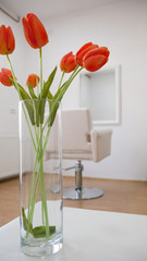 Bouquet of orange tulips in a hair salon - White hairdressing chair in front of the mirror in the background.