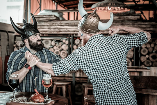 Two men in viking helmets punching each other.