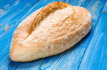 Whole loaf bread with crisp on wooden background top view