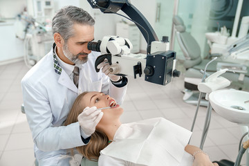 Male dentist looking at microscope and checking teeth