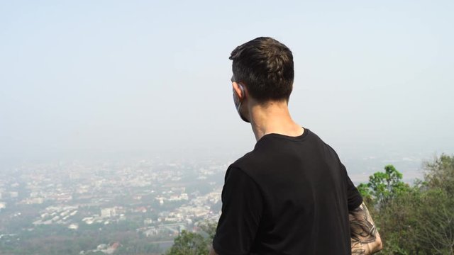 Young Tattooed Man wearing face mask because of Air pollution or virus epidemic in the city.
The pollution is causing poor visibility and smog covered all over the city.