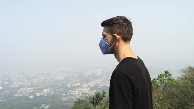 Chiang Mai young man wearing a face mask and looking at the city.