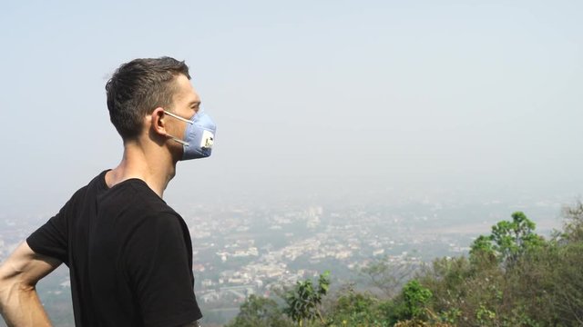Chiang Mai young tattooed man wearing a face mask to prevent the toxic air inhalation.