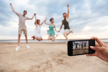 Group of a cheerful young friends jumping at the beach