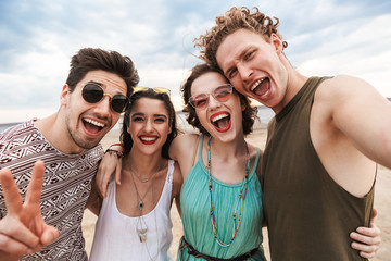 Group of a cheerful young friends walking at the beach