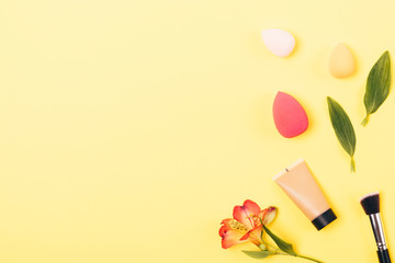 Foundation in tube next to tools for professional makeup: synthetic brush and blending sponges,...