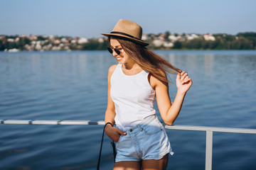 Obraz premium Cute young brunette girl relaxing on the pier near lake.