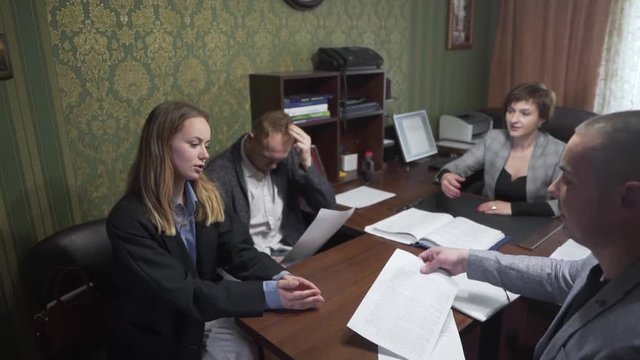 Young Caucasian Married Couple Sitting in Realtors Office With Real Estate Broker After Signing Contract for New Apartment Property. Light Camera Movement