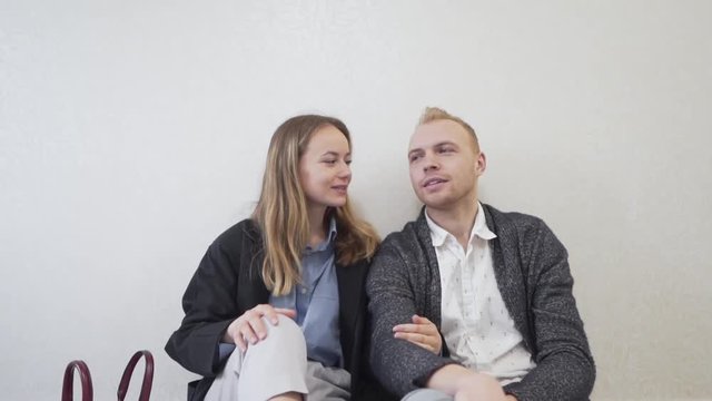Caucasian Married Couple Sitting on Floor of Empty Room of Their New Apartment Real Estate and Talking About Future Arragements. Light Pull Back Camera Movement