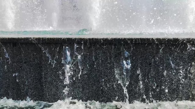 Water drops splashing on water surface in slow motion. Close up of water fountain. Water jet splashing