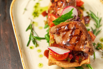 Grilled meat on pita bread on a bright oval plate. Dark wooden background. Restaurant menu