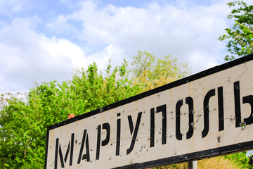 Road sign with the inscription in Ukrainian Mariupol, city of the Donetsk region, punched by bullets, Ukrainian war, conflict East Ukraine