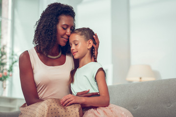 Obraz premium Close-up face portrait of mom affectionately cuddling cute little girl