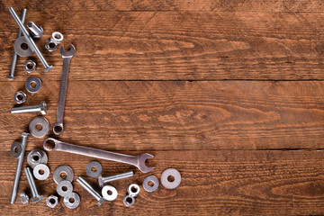 Keys wrenches, bolts, nuts, washers on a wooden background