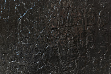 The surface of the wall is painted with black glossy oil paint over the old cracked and exfoliated. Surface of the dark paint is smoothed and shiny. Cracks in the form of lines of different shapes.