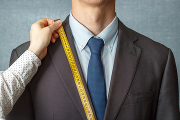 The tailor measures the suit with a measuring tape close-up
